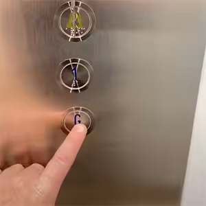 Finger pressing ground floor compass lift button.