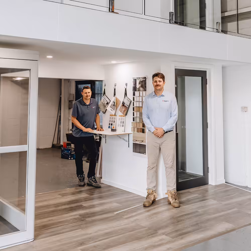 Two men in an office with flooring samples and Australian made home lifts.