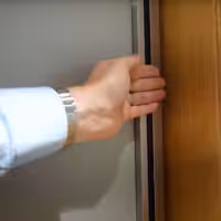 Hand closing a sliding wardrobe door with infrared safety feature