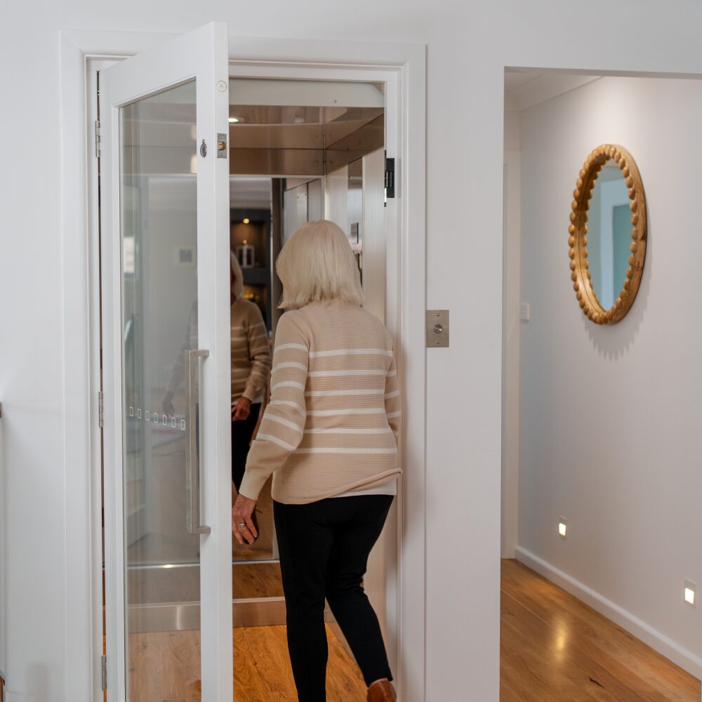 Elderly woman testing a home lift inside a residential property