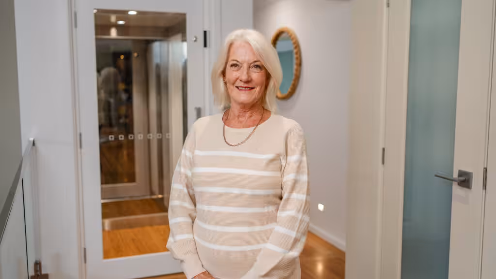 Newest client of Velocity Home Lifts smiling happily in front of their installed home lift