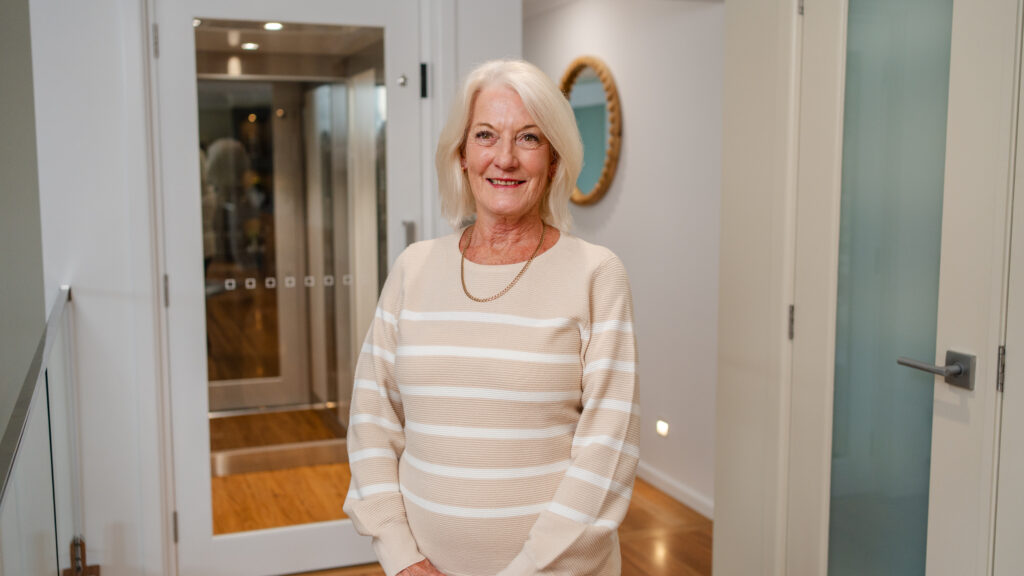 Newest client of Velocity Home Lifts smiling happily in front of their installed home lift